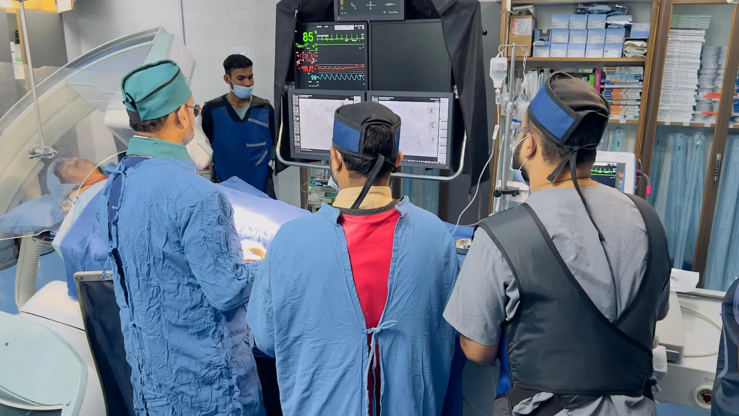 Cardiology team viewing angiography images and patient monitor in the cath lab