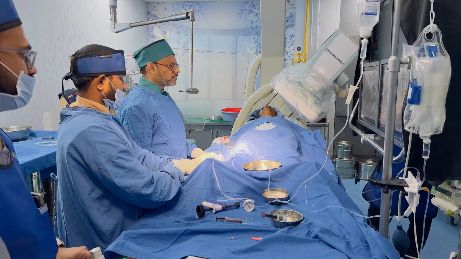 Cardiologist and team performing a procedure in the cath lab with an angiography system